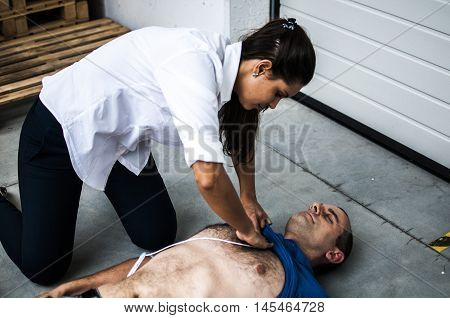 girl applying defibrillator pads to an unconscious man after heart attack