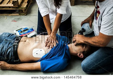 operators helping an unconscious man with defibrillator after heart attack