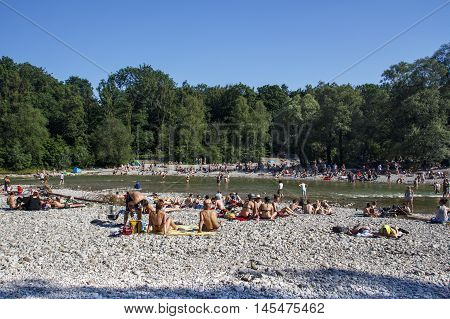 MUNICH, GERMANY - JUNE 4, 2015: The Isar river in Munich with many unidentified people on a sunny day taking a sunbath