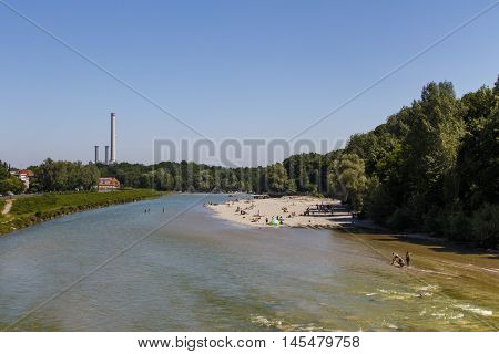 The Isar river in Munich with many unidentified people on a sunny day taking a sunbath