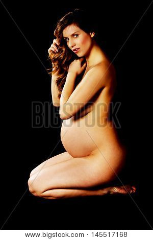 Beautiful pregnant woman kneeling on the floor.