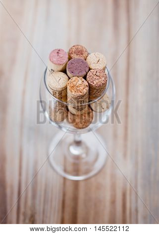 Wine corks in a glass of wine on a wooden table