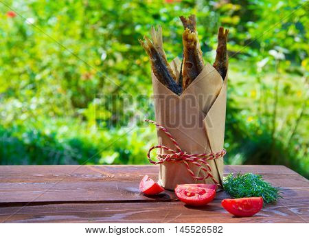 Lunch in nature, fried fish in a paper cup, with tomato and fennel