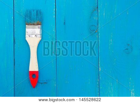 Large paint brush with wooden handle and blue wooden backgraund