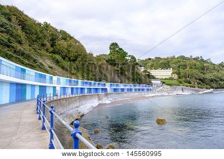 Lovely seaside scene at Meadfoot Bay Torquay in Devon England with its colorful blue beach huts sheltered by trees
