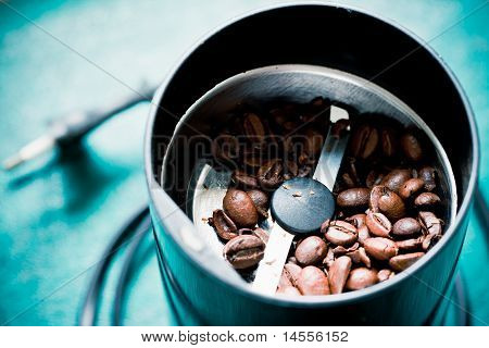 Elektrische koffiemolen machine met geroosterde koffiebonen op de groene tafel komen zonder bovenklep