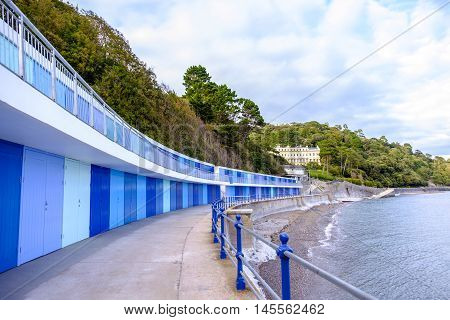 Beautiful row of colorful blue beach huts by the sea at Meadfoot Bay in the English Riviera town of Torquay Devon England