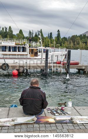 Queenstown New Zealand - March 2016: Artist working at Queenstown lakefront by Lake Wakatipu New Zealand