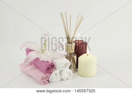 Spa decoration with candles towels and aromatherapy oil bottle on white background with lily