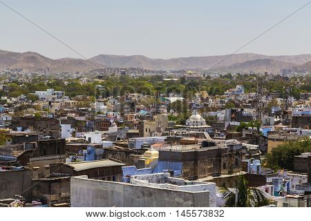 A view over rooftops in central Udaipur during the day. The Machla Hills can be seen in the distant.