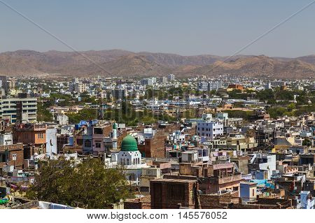 A view over rooftops in central Udaipur during the day. The Machla Hills can be seen in the distant.