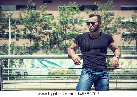 Handsome muscular blond man standing in city setting or former industrial environment