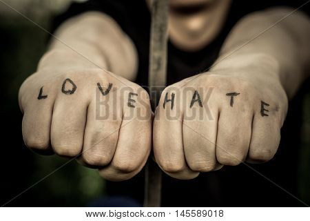 Man stretching his arms forward. Hands clenched into fists. In the hands of inscribed words "love" and "hate"