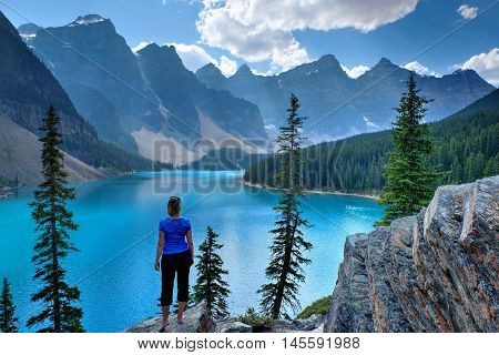 Woman on cliff at Moraine Lake in Rocky Mountain. Banff National Park Alberta Canada.