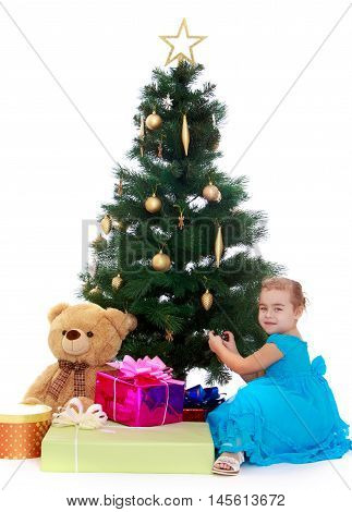 Happy little girl near a Christmas tree surrounded by gifts isolated on white background
