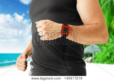 Man with pulsometer on blurred ocean coast background