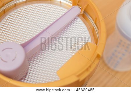 can of powdered milk and baby bottle for children on wooden table