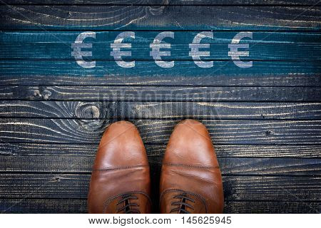 Euro sign message and business shoes on wooden floor