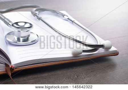 Stethscope on top of notebook with wooden background