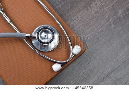 Stethscope on top of brown notebook with wooden background