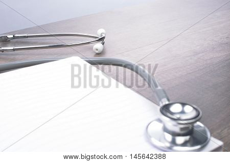 Stethscope on top of notebook with wooden background