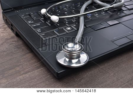 Stethscope on top of laptop with wooden background