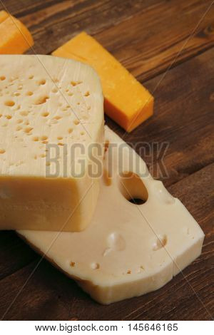 various types of fresh raw aged delicatessen cheese on wooden table cheddar edam swiss