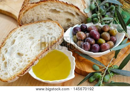 Traditional italian appetizer - fresh homemade bread extra virgin olive oil and olives on wooden background