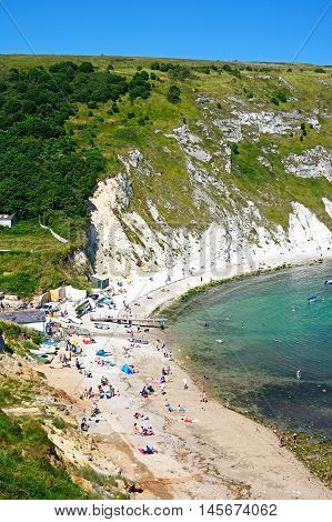 LULWORTH COVE, UNITED KINGDOM - JULY 19, 2016 - View looking down the hillside towards the cove with tourists enjoying the beach Lulworth Cove Dorset England UK Western Europe.