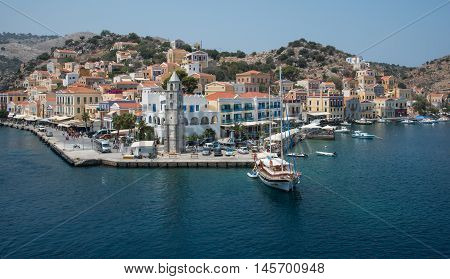 Symi Greece - August 1 2016: Panoramic image of Symi town with the harbor and the colorful houses on the hill in the Greek Island of Symi at the Aegean sea.