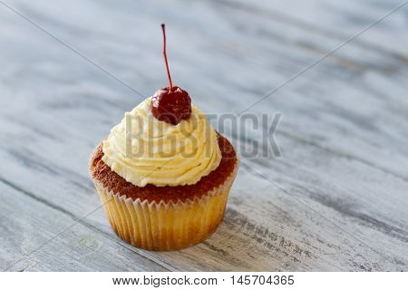 Cupcake with beige cream. Small dessert on wooden surface. Lift your mood with sweets. Snack at the pastry cafe.