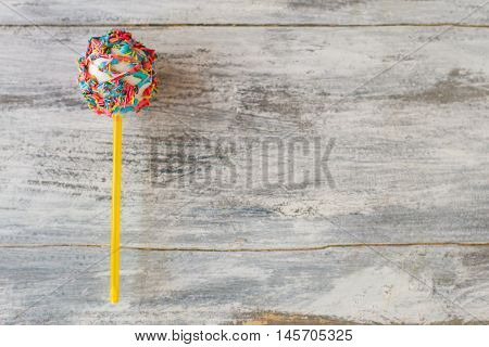 Cake pop with sprinkles. Candy on gray background. Eat well and have fun. Boost your mood.