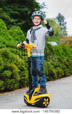 Happy boy standing on hoverboard or gyroscooter outdoor.