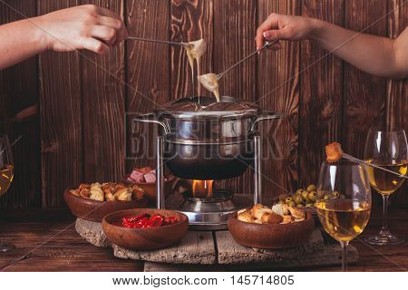 Delicious Cheese Fondue on a fork on a wooden stand