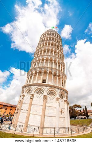Famous leaning tower with italian flag on the sky background in Pisa in Italy