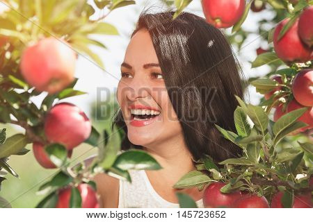 Beautiful woman standing  in her organic apple orchard, close up, selective focus