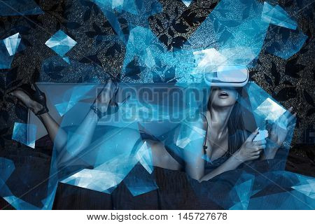 Sexy young woman using VR headset and remote control in bed at night
