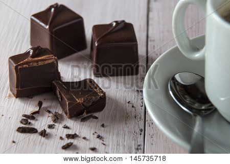 Three chocolate candies and a cup of coffee on a wooden table