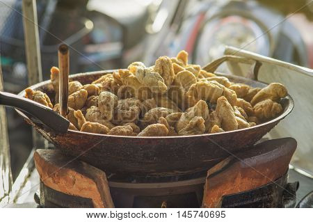 thai local street foodfried rugby fish ball in a hot pan,light effect added,selective focus,warm tone process