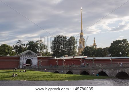 Sankt-Petersburg Russia - AUGUST 26  2016: The spire of the Peter and Paul fortress the entrance to the fortress and resting people
