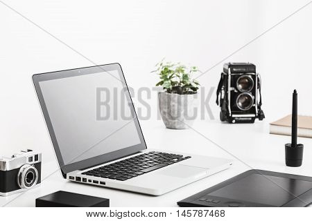 Photographer's desk with laptop, vintage camera and tablet. Modern and retro technology. White background.