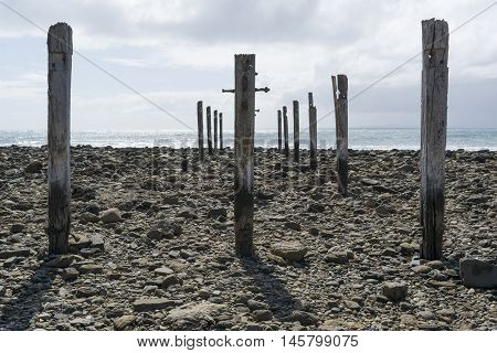 Low tide fully exposing the pylon pillar posts gradually decaying in the sunshine from the old jetty ruins at Myponga Beach South Australia.