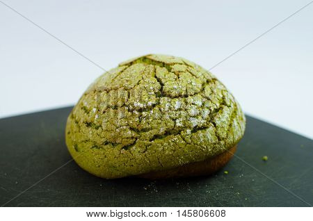 Japanese bread matcha melon pan on black cutting board