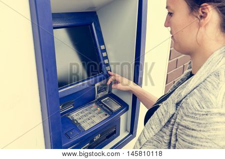 Attractive brunette withdrawing money. Entering pin number.
