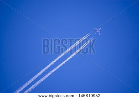 A plane flying on a perfectly blue sky with vapor trail