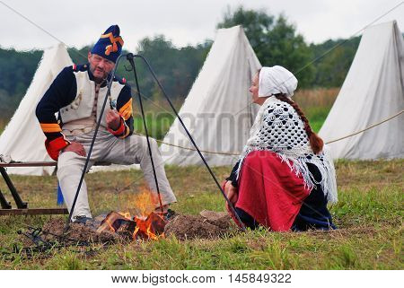 BORODINO MOSCOW REGION - SEPTEMBER 04 2016: Reenactors man and woman sit by the fire at Borodino battle historical reenactment in Russia. Color photo.