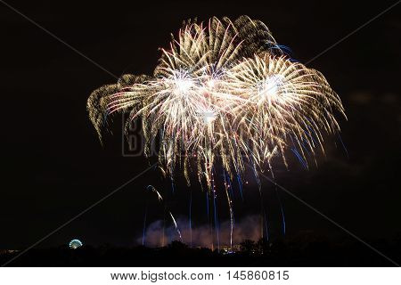 Bright fireworks with ferries wheel to the left - celebrating New Year or other festivities - abstract holiday background