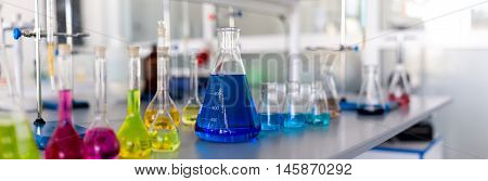 Laboratory table piled tubes with colored liquid colored reagents in flasks and test tubes