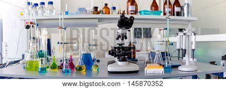 Laboratory table piled tubes with colored liquid colored reagents in flasks and test tubes