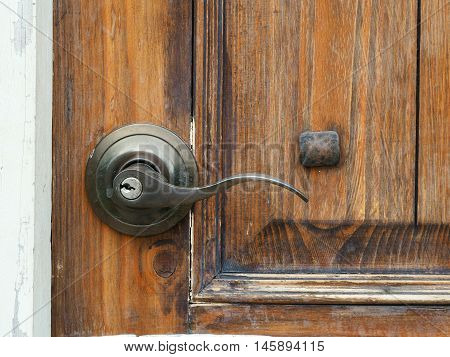 The old metal door handle on the wooden door